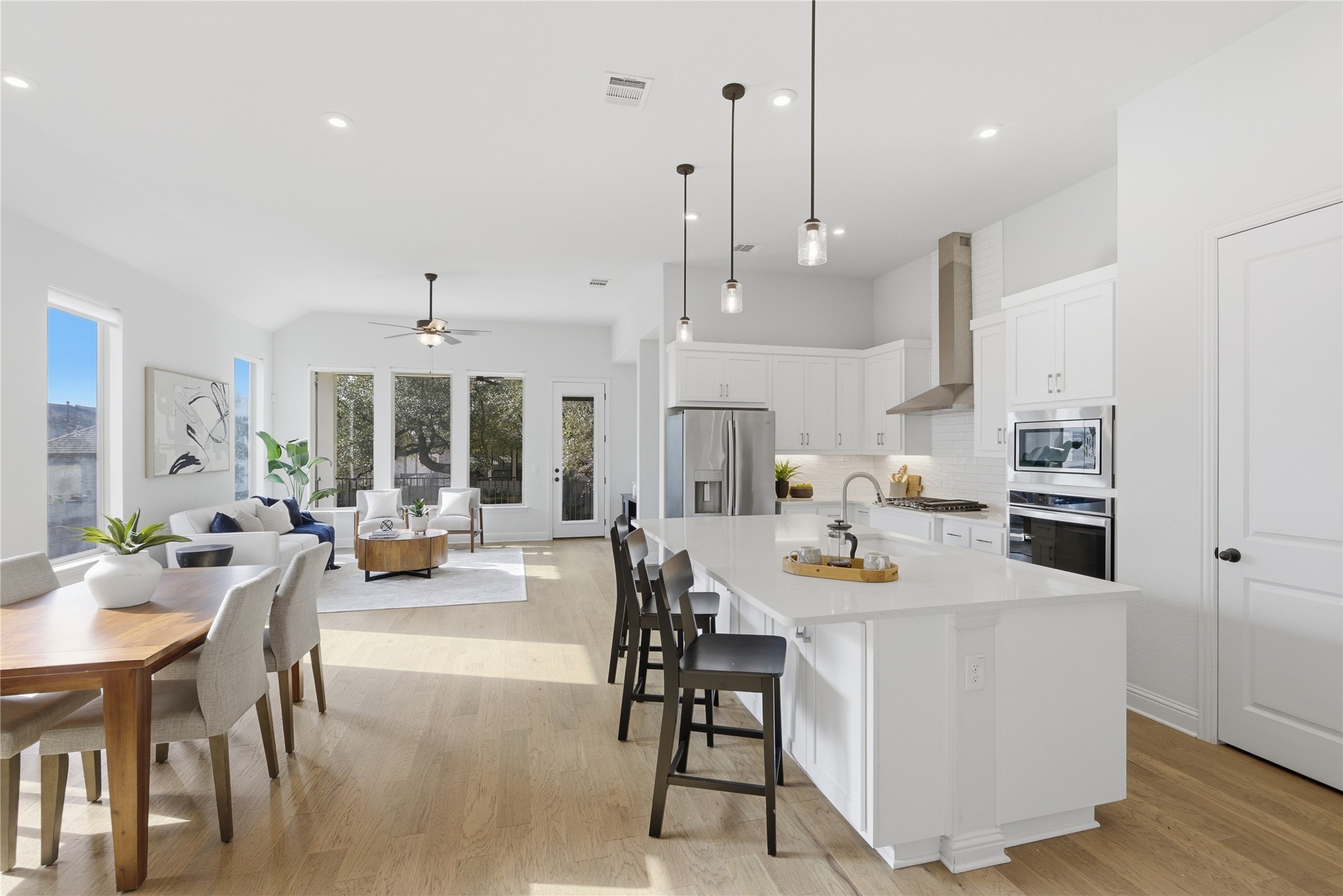 225 Diamondback Drive Georgetown, TX 78628 - Photo 6 of 39 Kitchen with light wood-style flooring, stainless steel appliances, white cabinets, a breakfast bar with sink, and pendant lighting.