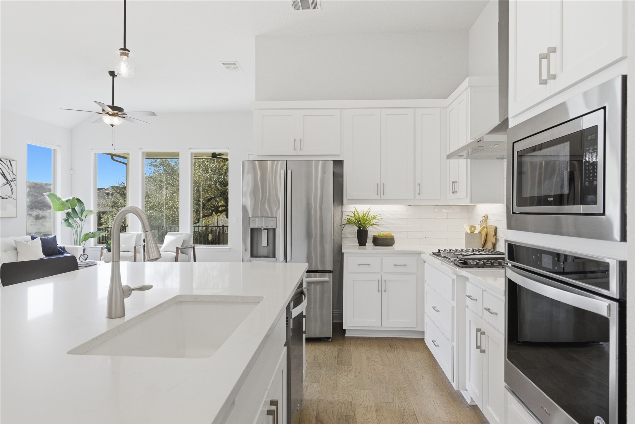 225 Diamondback Drive Georgetown, TX 78628 - Photo 7 of 39 Kitchen with light wood-style flooring, stainless steel appliances, white cabinets, a breakfast bar with sink, and pendant lighting.