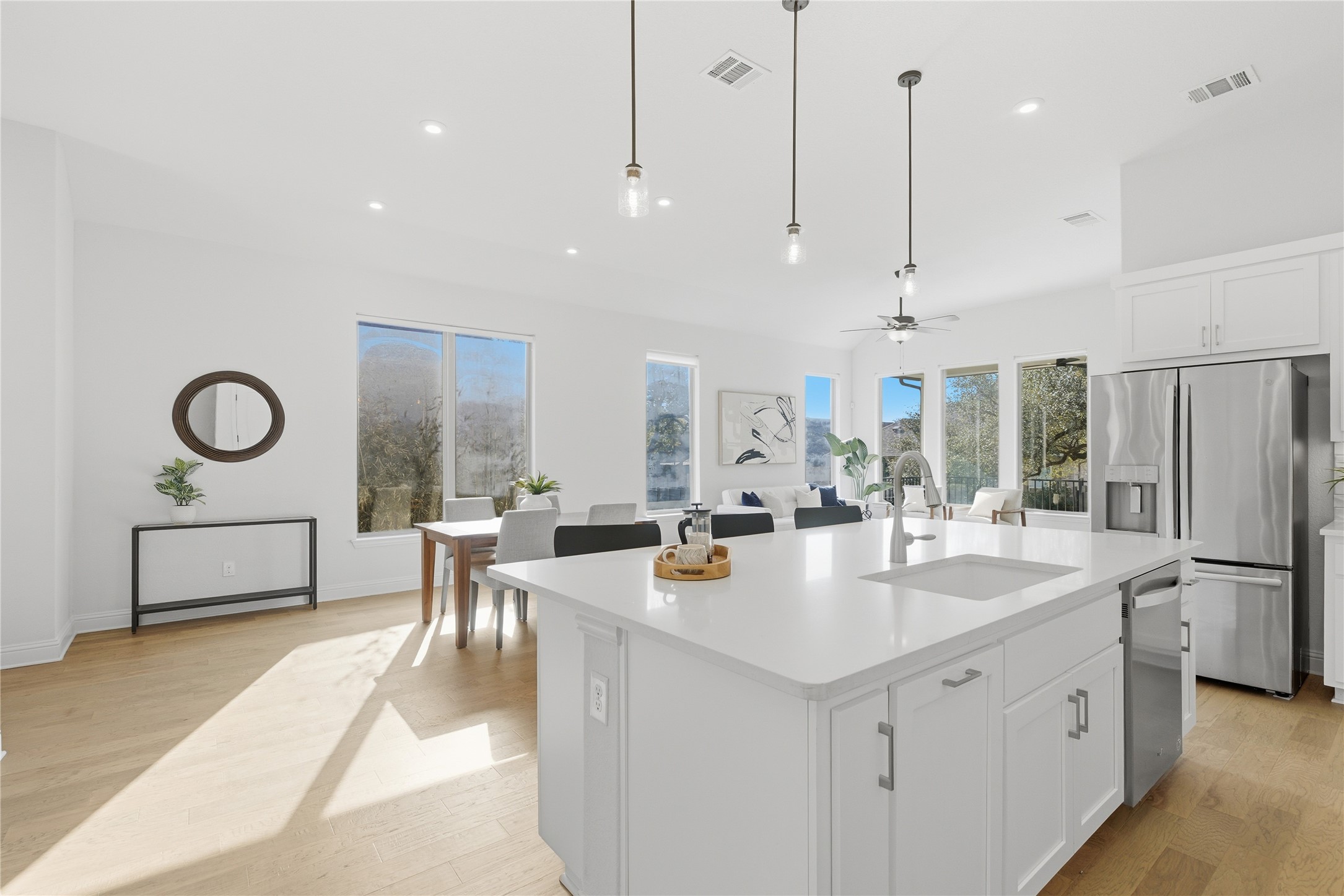 225 Diamondback Drive Georgetown, TX 78628 - Photo 8 of 39 Kitchen with light wood-style flooring, stainless steel appliances, white cabinets, a breakfast bar with sink, and pendant lighting.
