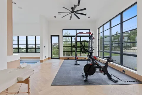 a living room with large windows and ceiling fan