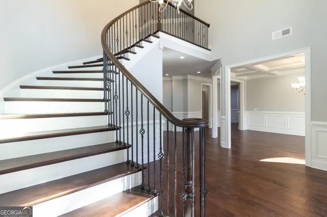 a view of an empty room with wooden floor and a kitchen