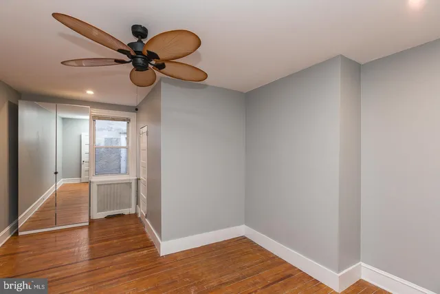 a view of a room with wooden floor and a ceiling fan