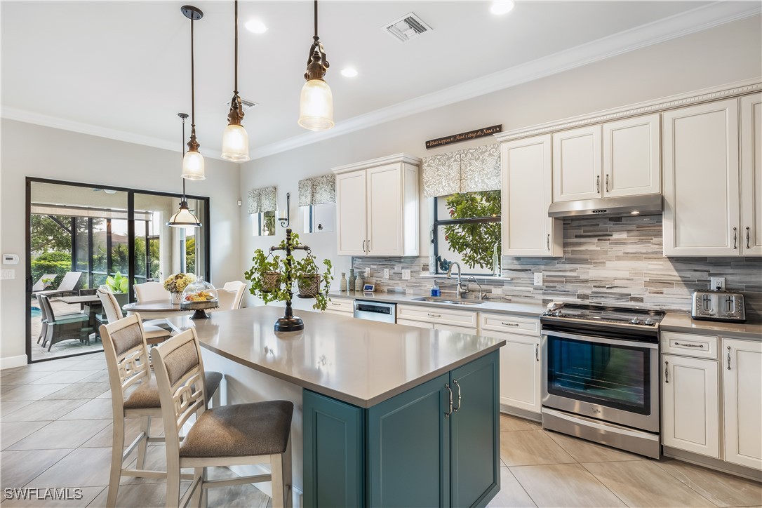 12894 Epping Way Fort Myers, FL 33913 - Photo 13 of 49 a kitchen with a stove a sink a kitchen island with chairs and wooden cabinets