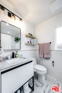 a bathroom with a granite countertop toilet sink and mirror