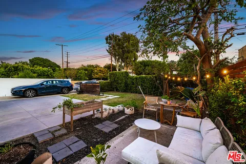 a view of a patio with table and chairs potted plants and a large tree