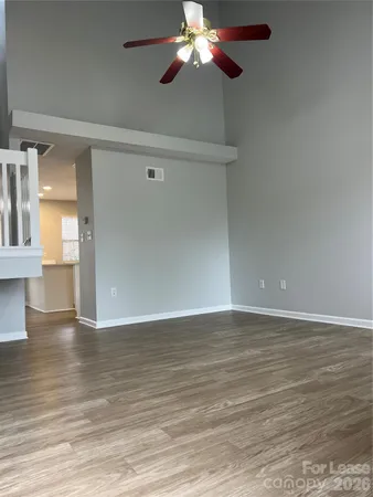 a view of an empty room with wooden floor and a ceiling fan