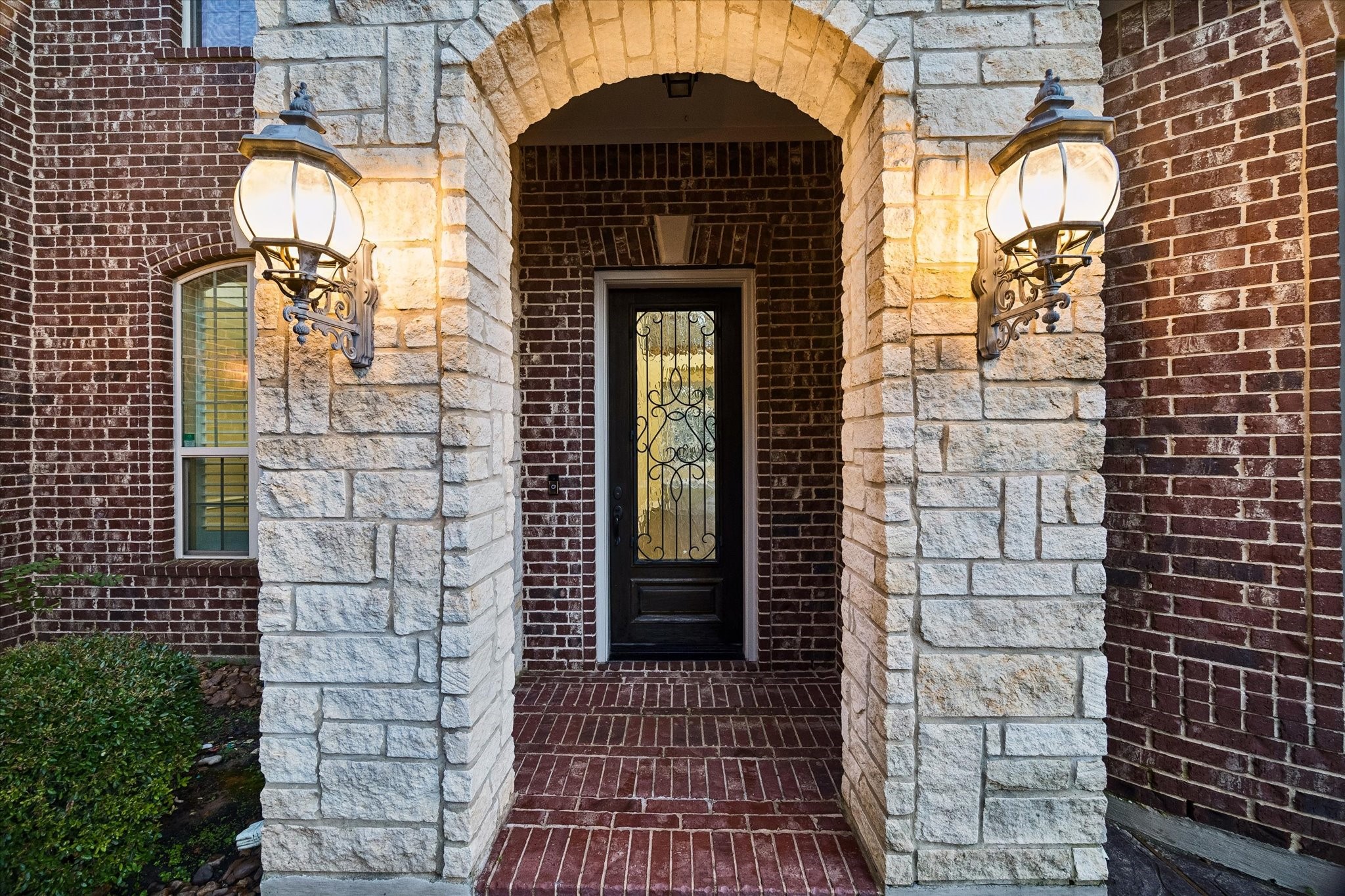 35 North Fremont Ridge Loop Spring, TX 77389 - Photo 2 of 37 The elegant entry welcomes guests with timeless architectural details, including a custom iron-and-glass front door, warm lantern-style lighting, and a beautiful combination of rich brick and natural stone finishes.