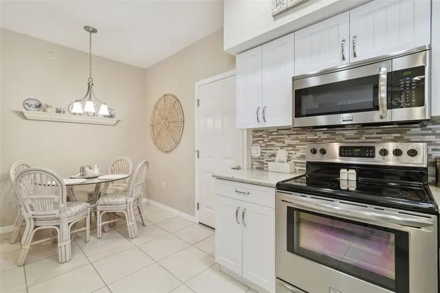 a dining room with stainless steel appliances furniture and a chandelier