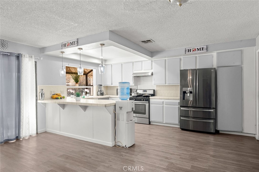15811 Hercules Street Hesperia, CA 92345 - Photo 14 of 43 a kitchen with a refrigerator and white cabinets