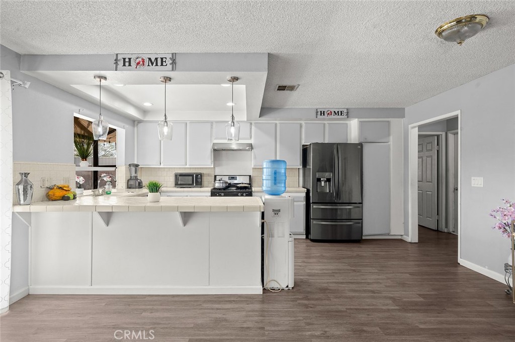 15811 Hercules Street Hesperia, CA 92345 - Photo 15 of 43 a kitchen with stainless steel appliances a refrigerator and a stove top oven