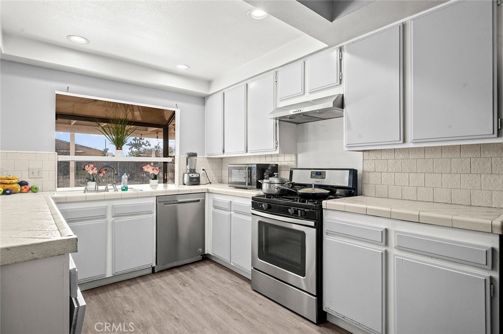 15811 Hercules Street Hesperia, CA 92345 - Photo 16 of 43 a kitchen with a stove white cabinetry and a sink