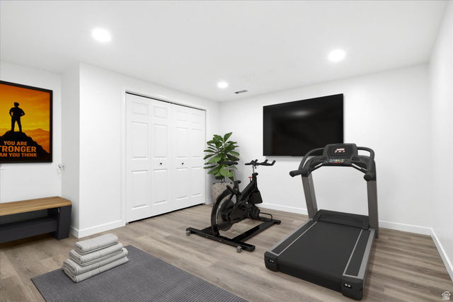 1676 East 11245 South Sandy, UT 84092 - Photo 27 of 34 Dedicated fitness space featuring light wood-finish flooring, bright white walls, and recessed ceiling lighting. This room does not have a window but could be used for many things including an optional bedroom. This photo is virtually staged.