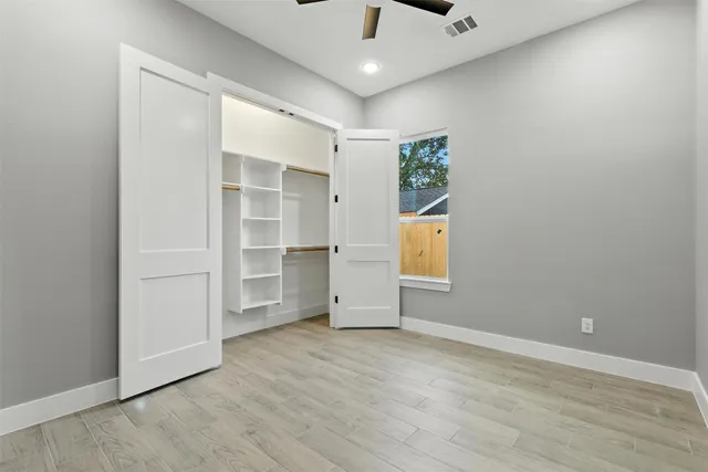 a view of an empty room with a window and wooden floor
