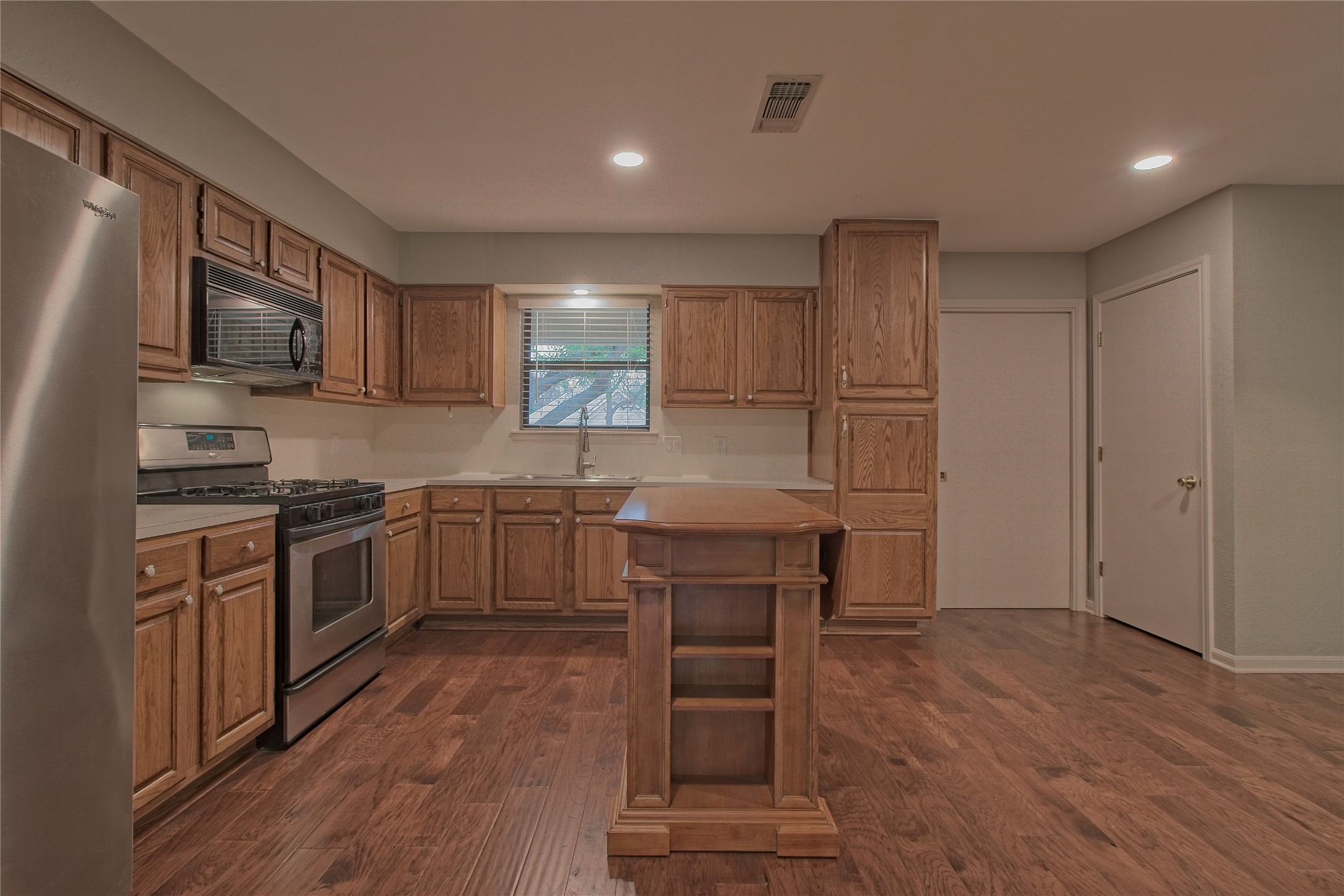 1102 Fowzer Street Taylor, TX 76574 - Photo 13 of 27 Kitchen featuring stainless steel appliances, light countertops, dark wood-type flooring, recessed lighting, and wood finish cabinetry