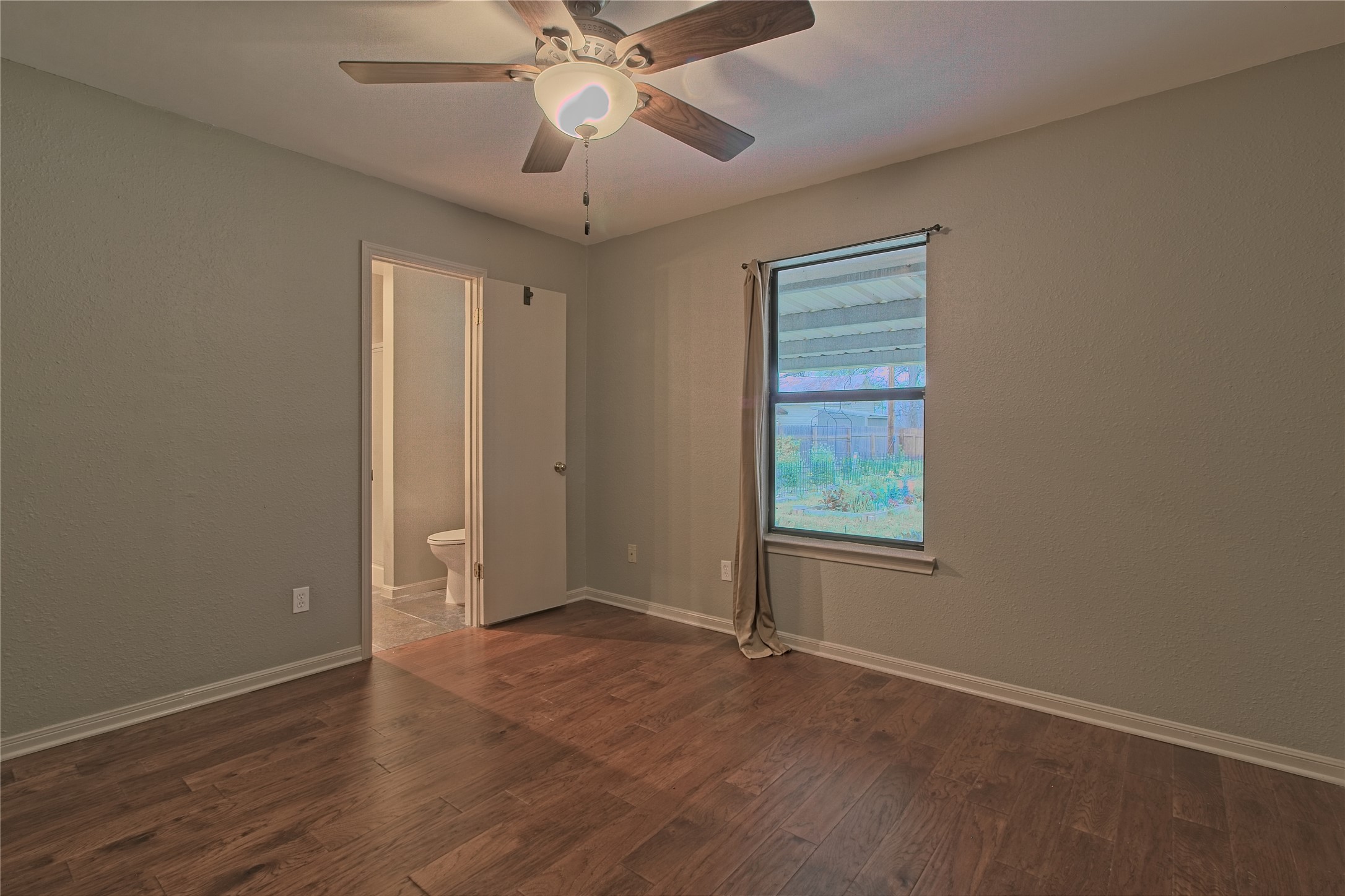 1102 Fowzer Street Taylor, TX 76574 - Photo 16 of 27 Unfurnished room featuring a ceiling fan, dark wood-style floors, and a textured wall