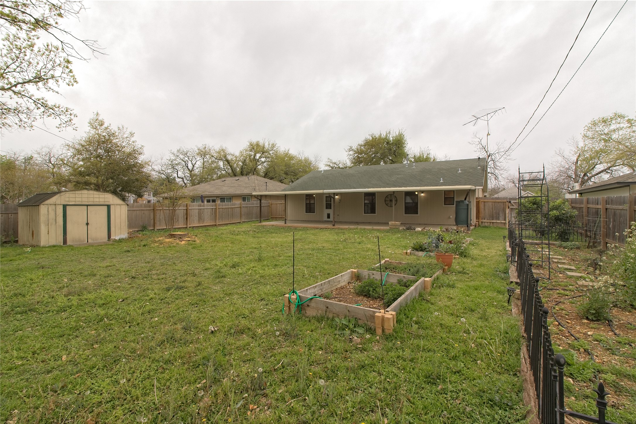 1102 Fowzer Street Taylor, TX 76574 - Photo 23 of 27 Back of house featuring a garden, a fenced backyard, a shed, and a patio