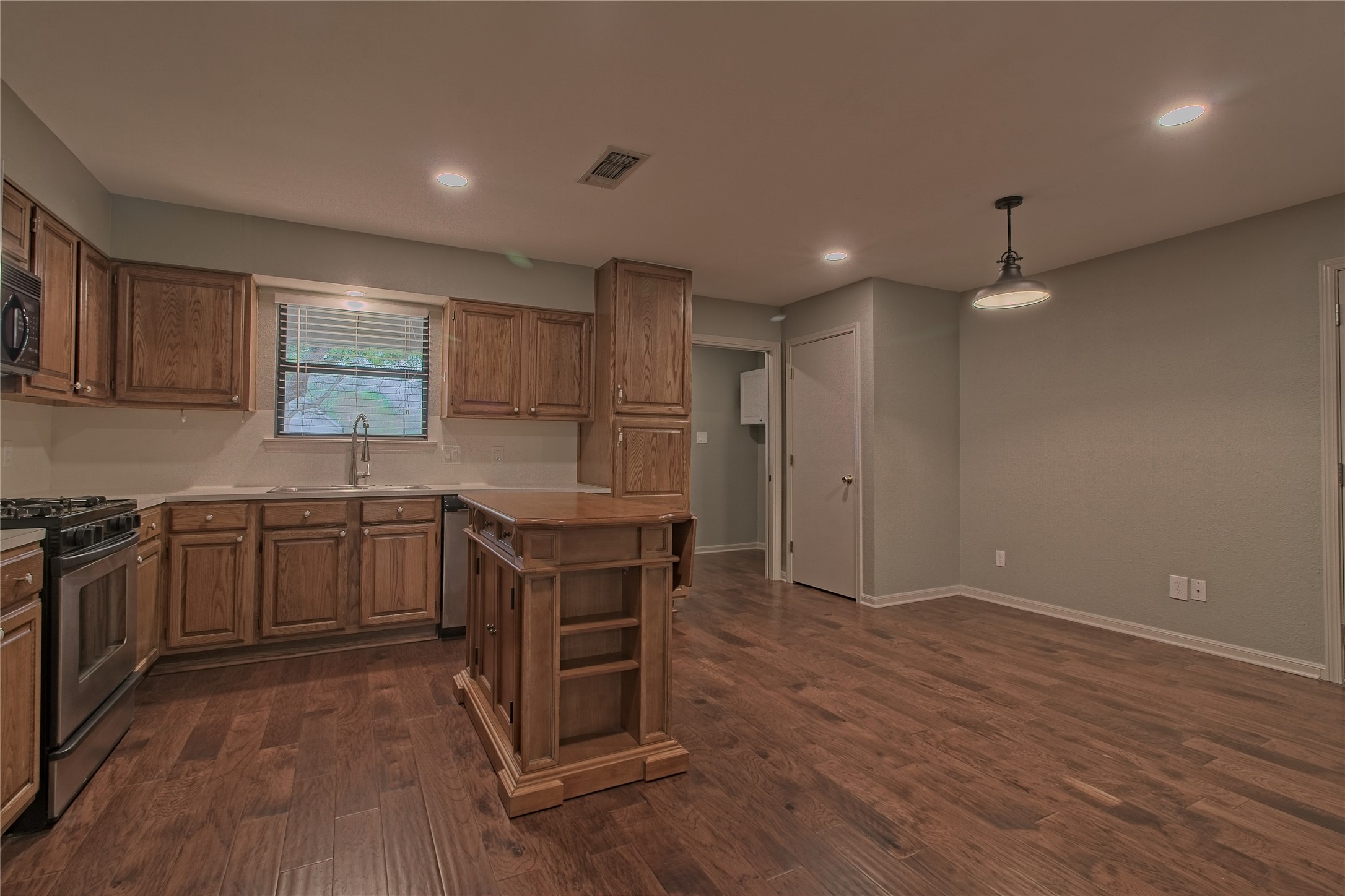 1102 Fowzer Street Taylor, TX 76574 - Photo 9 of 27 Kitchen with light countertops, stainless steel appliances, hanging light fixtures, and wood finish cabinetry