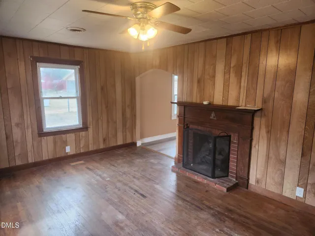 an empty room with wooden floor fireplace and windows