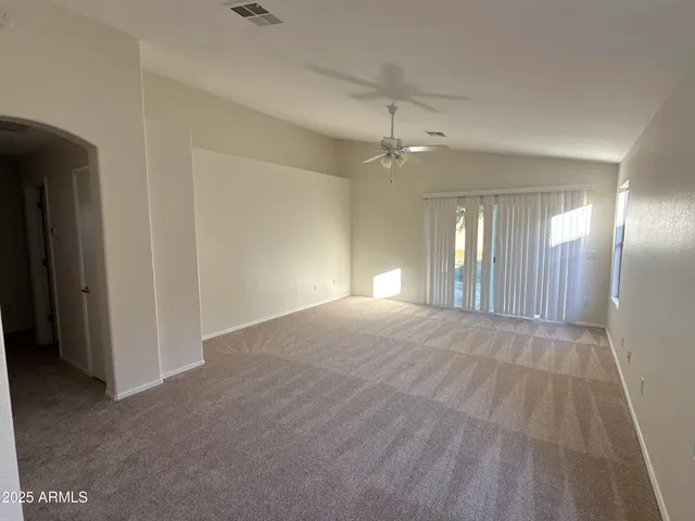 a view of empty room with window and chandelier fan