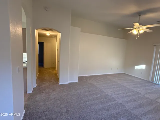 a view of an empty room and chandelier fan