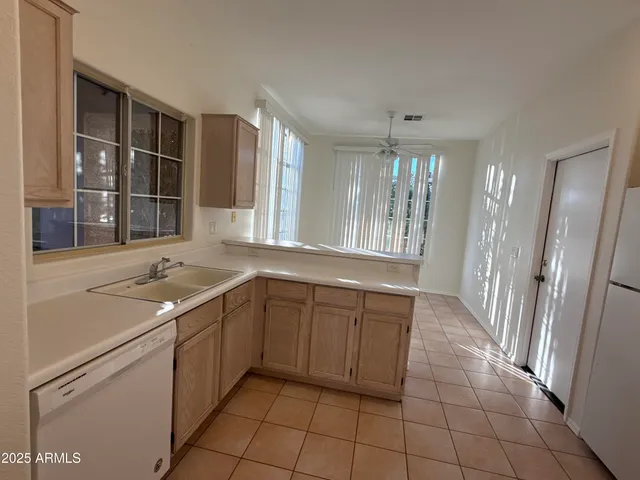 a large white kitchen with a sink and large window