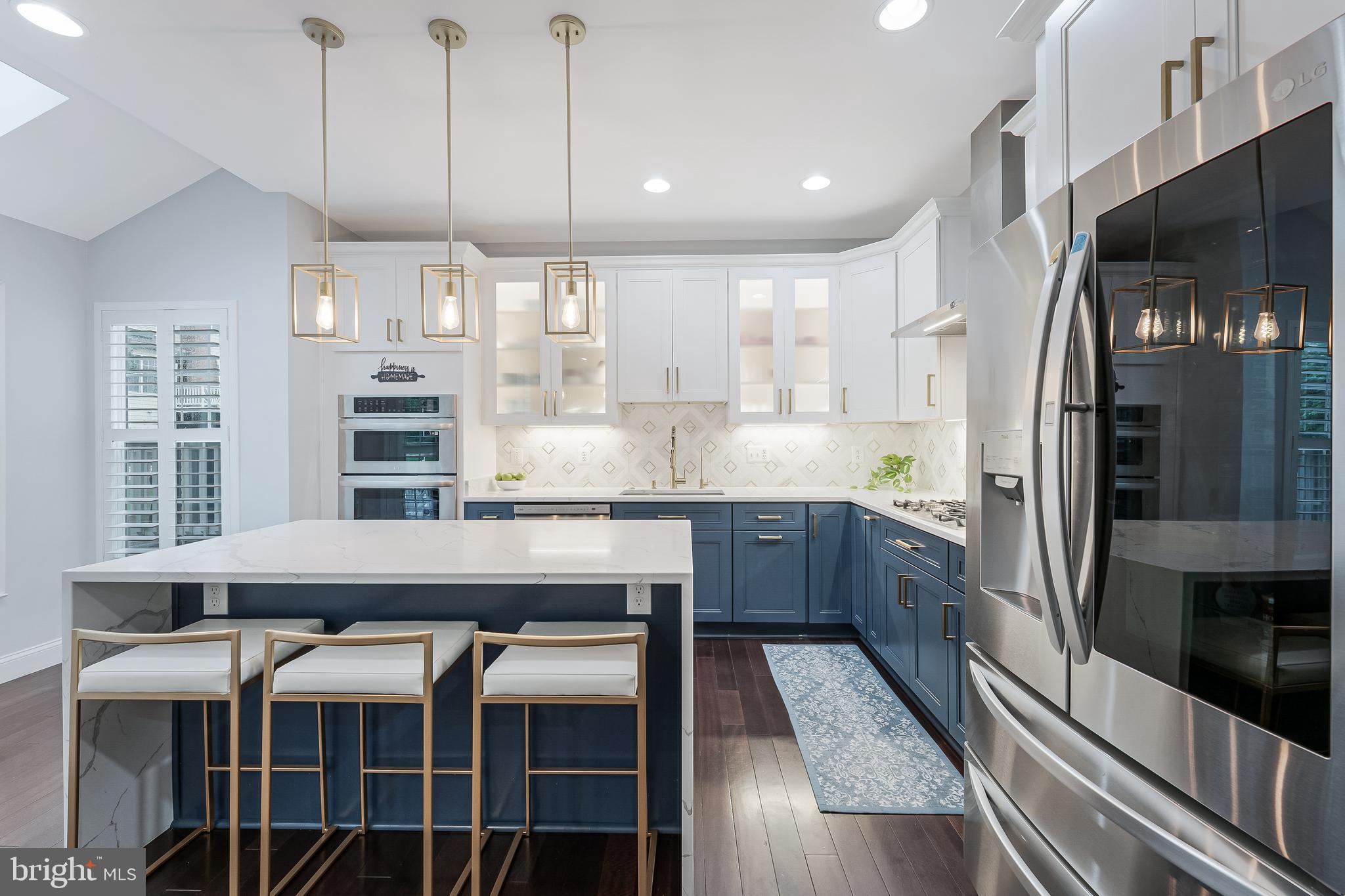 19599 Aspendale Square Ashburn, VA 20147 - Photo 8 of 56 a kitchen with stainless steel appliances kitchen island granite countertop a table chairs in it and wooden floors