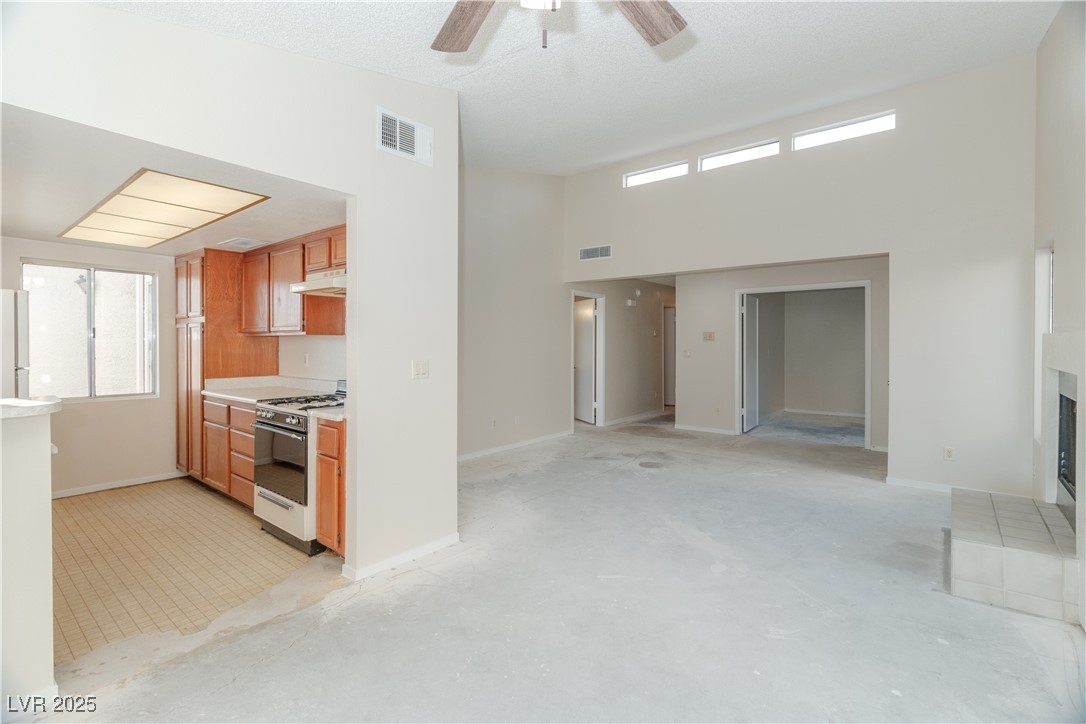 2225 Pebble Creek Lane Laughlin, NV 89029 - Photo 12 of 87 Kitchen featuring light countertops, gas stove, brown cabinetry, a fireplace with raised hearth, and a ceiling fan