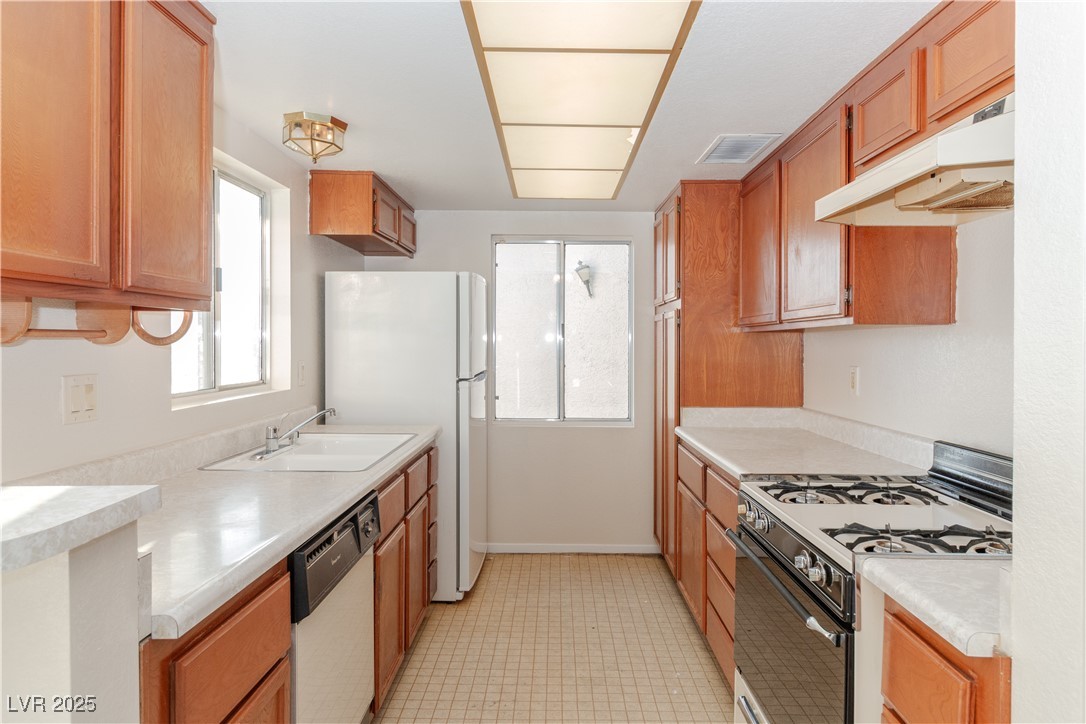 2225 Pebble Creek Lane Laughlin, NV 89029 - Photo 13 of 87 Kitchen with white appliances, under cabinet range hood, light countertops, and brown cabinets