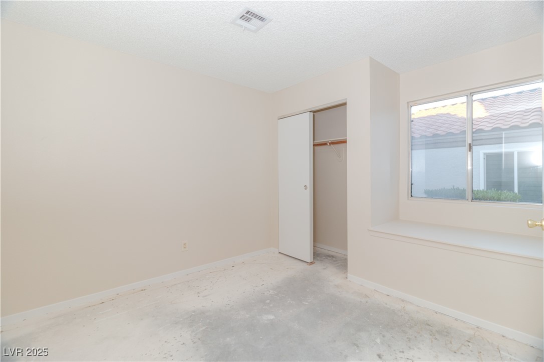 2225 Pebble Creek Lane Laughlin, NV 89029 - Photo 27 of 87 Second bedroom featuring a textured ceiling, concrete flooring, and a closet