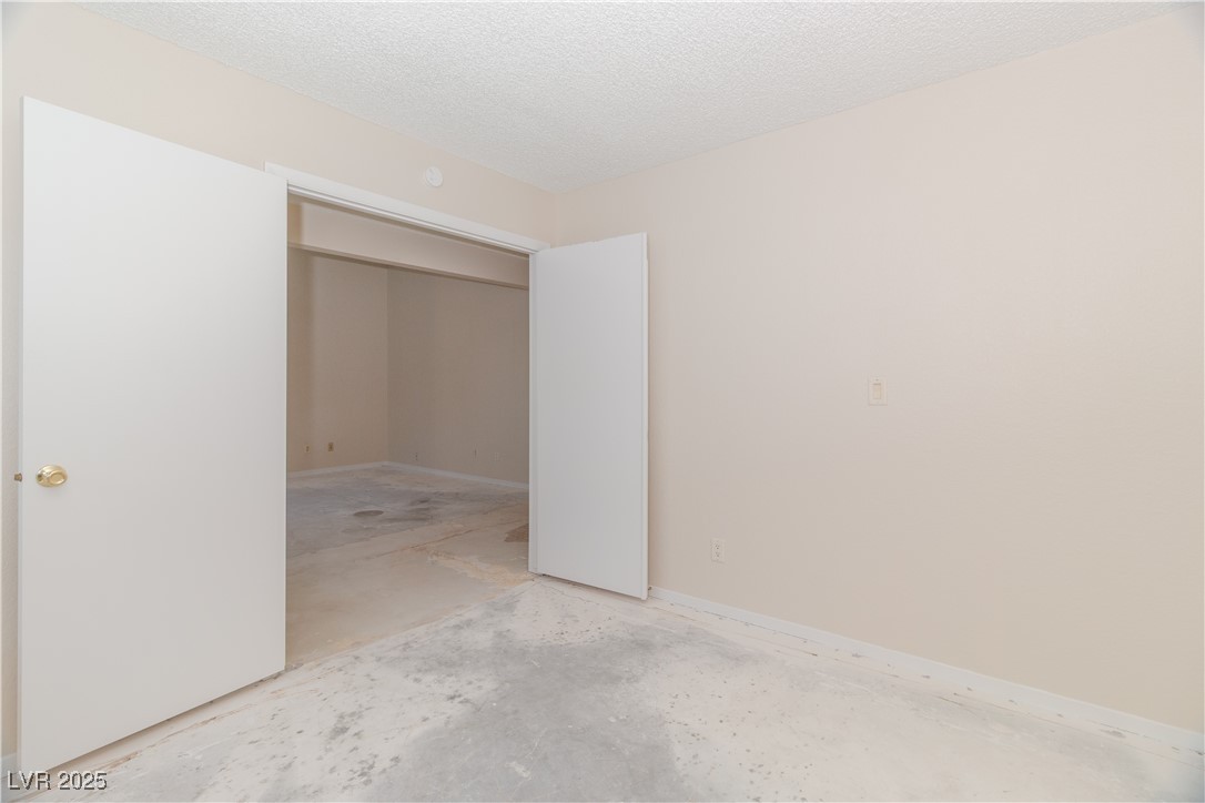 2225 Pebble Creek Lane Laughlin, NV 89029 - Photo 29 of 87 Second bedroom featuring concrete flooring, a textured ceiling, and a closet