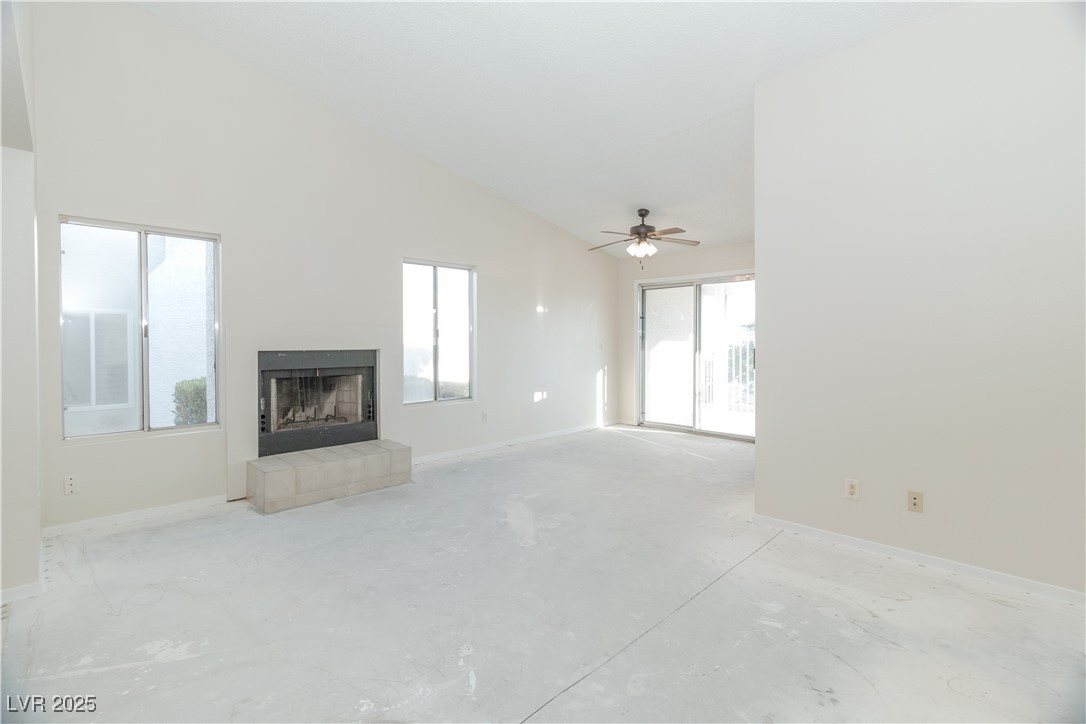 2225 Pebble Creek Lane Laughlin, NV 89029 - Photo 7 of 87 Unfurnished living room featuring a fireplace, plenty of natural light, high vaulted ceiling, concrete floors, and ceiling fan