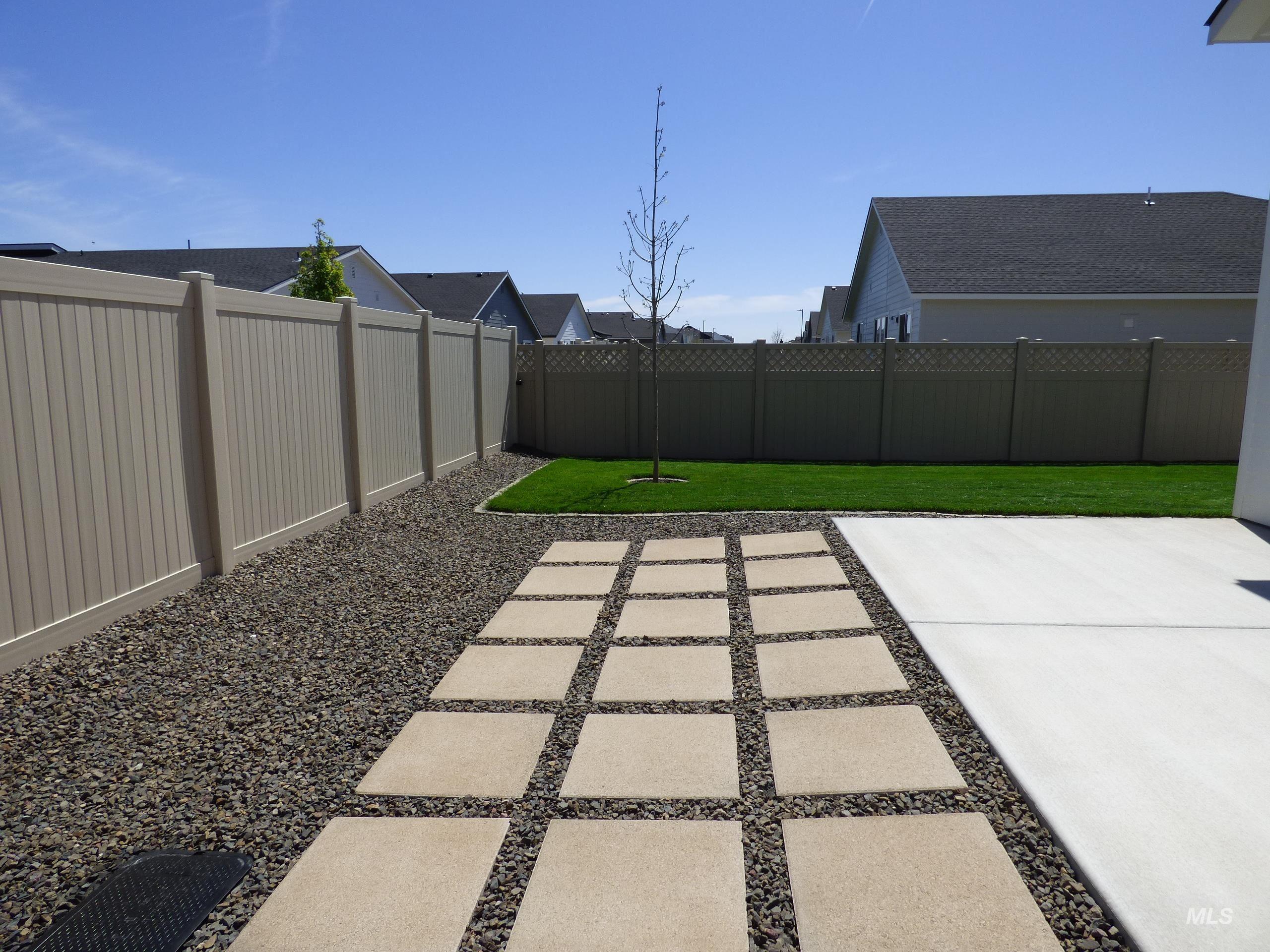 2708 East Buckaroo Drive Kuna, ID 83634 - Photo 42 of 48 Expansive backyard featuring a concrete patio, a paver walkway with gravel infill, and a manicured lawn
