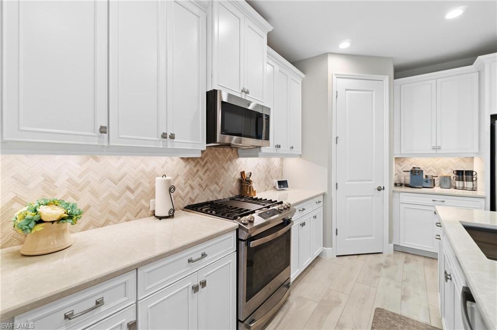 2298 Marquesa Circle Naples, FL 34112 - Photo 4 of 50 a kitchen with granite countertop white cabinets and stainless steel appliances