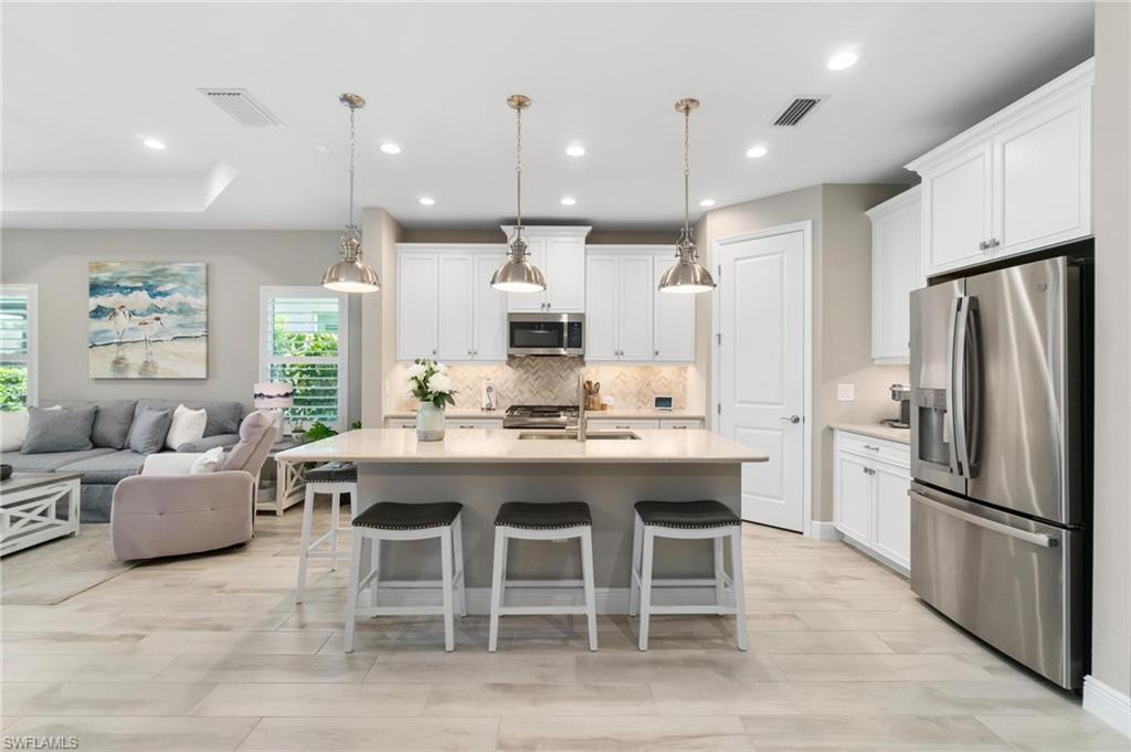 2298 Marquesa Circle Naples, FL 34112 - Photo 6 of 50 a kitchen with stainless steel appliances kitchen island granite countertop a dining table and chairs