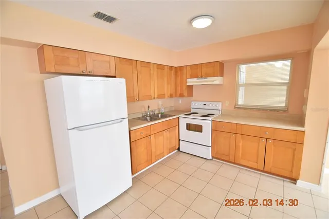 a kitchen with a refrigerator a stove top oven and cabinets