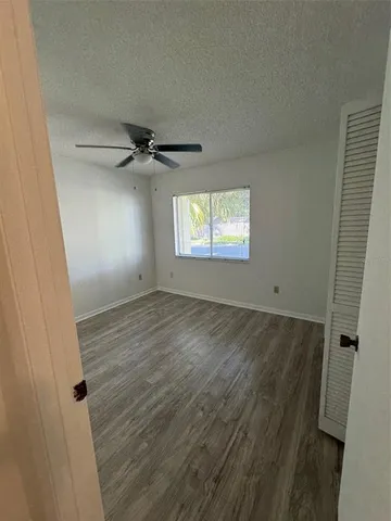an empty room with wooden floor closet and windows