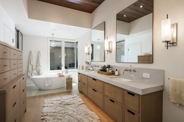 a bathroom with a double vanity sink mirror and bathtub