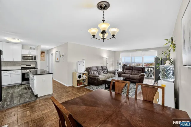 a living room with furniture kitchen view and a chandelier