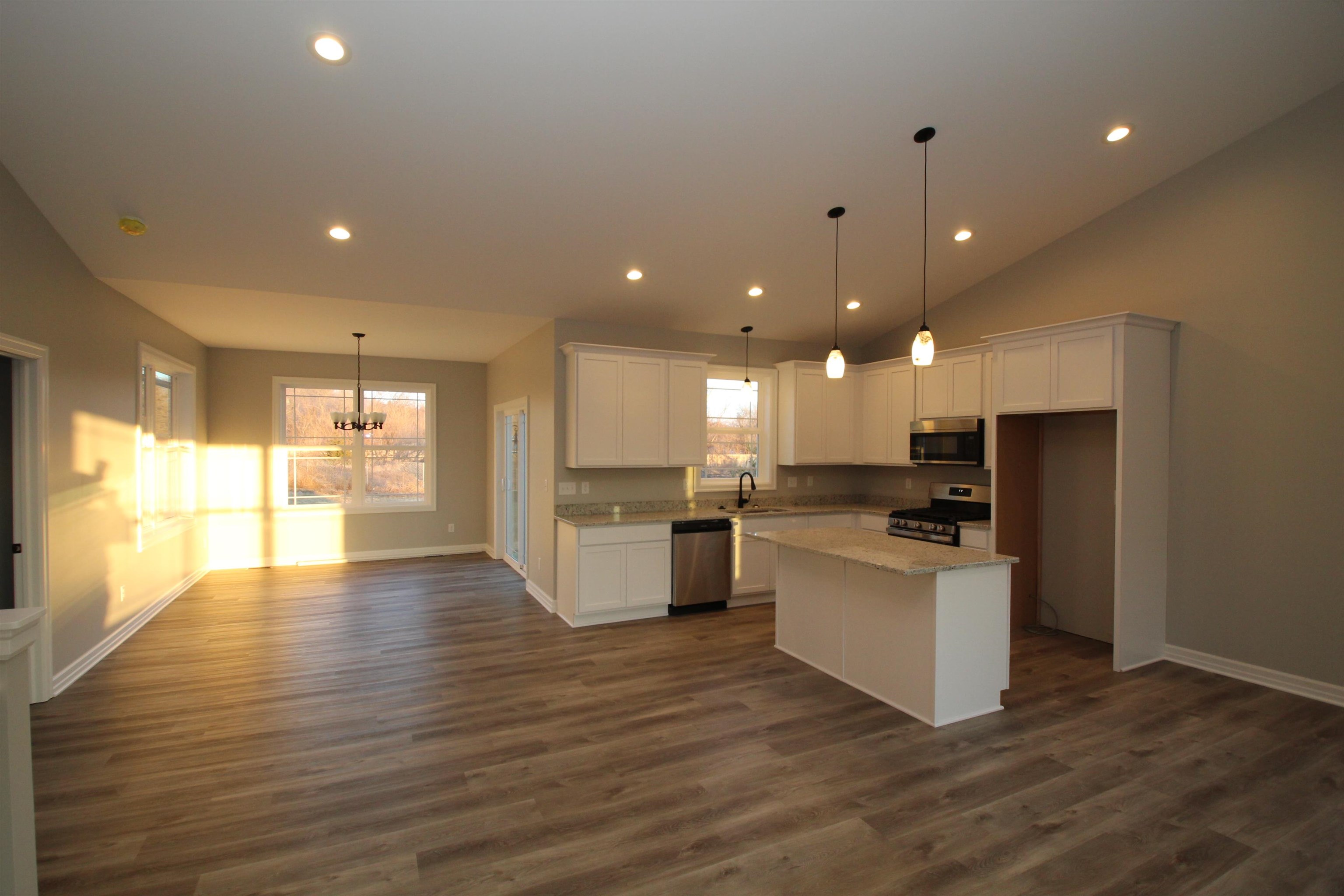 11235 Dublin Drive Roscoe, IL 61073 - Photo 4 of 20 a view of a kitchen with kitchen island a sink wooden floor and a large window