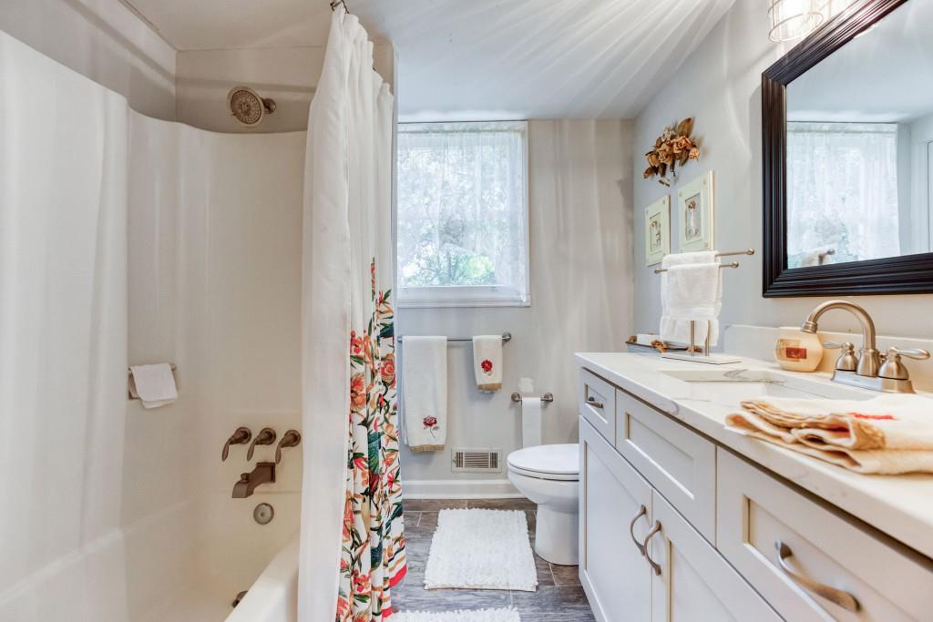 304 Edwards Street Monroe, GA 30655 - Photo 33 of 64 a bathroom with a granite countertop sink a toilet a mirror a vanity and shower