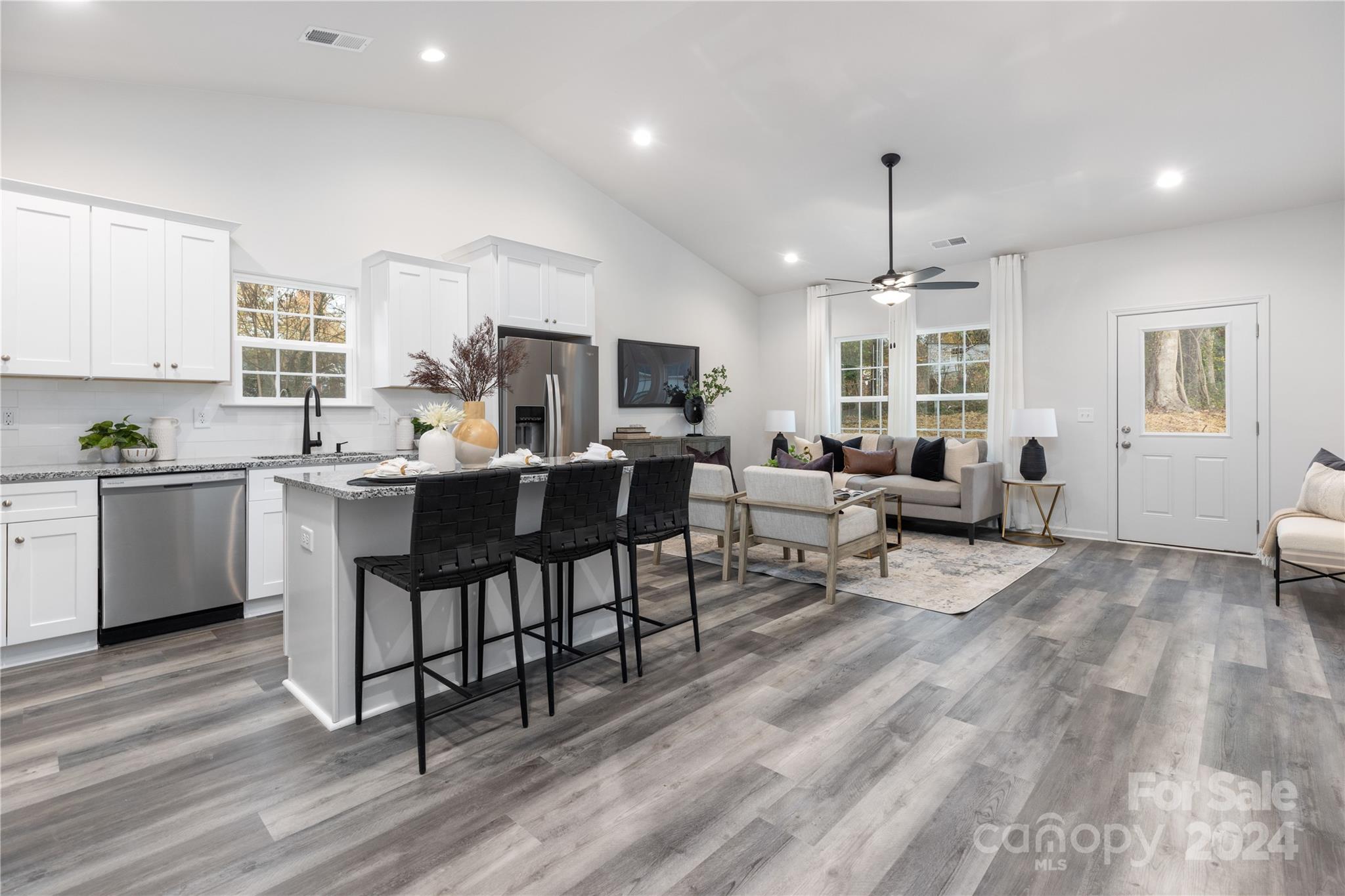 a living room with stainless steel appliances kitchen island granite countertop furniture and a wooden floors