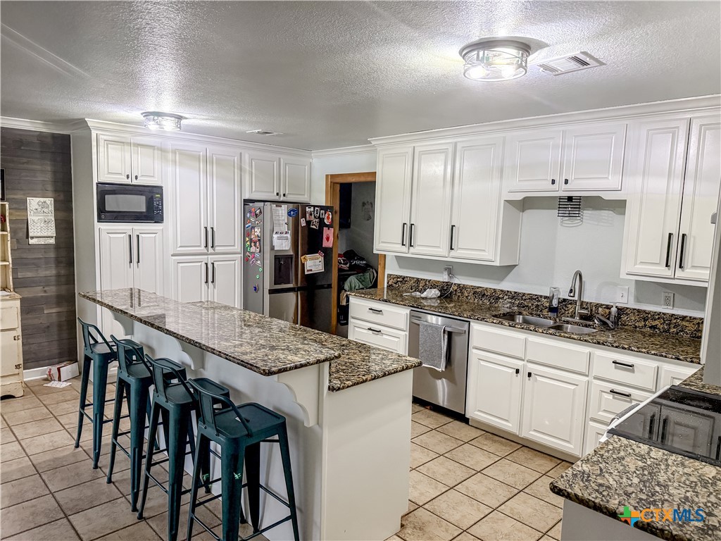 508 Straws Mill Road Gatesville, TX 76528 - Photo 6 of 26 a kitchen with stainless steel appliances kitchen island granite countertop a stove a sink a refrigerator and white cabinets