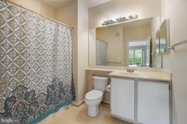 a bathroom with a granite countertop sink toilet a mirror and shower curtain