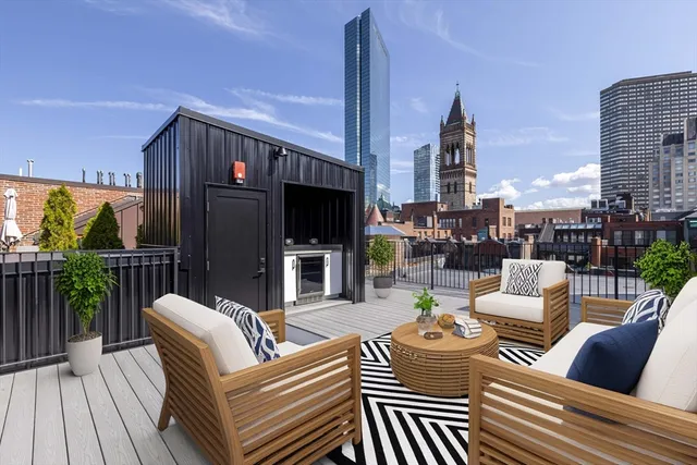 a view of a rooftop deck with couches chairs potted plants and wooden floor