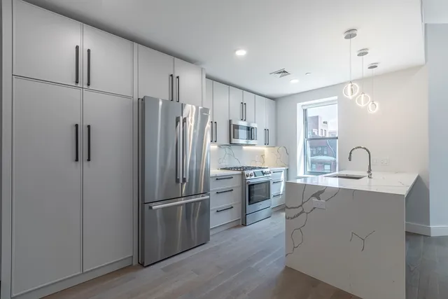 a kitchen with stainless steel appliances granite countertop a refrigerator sink and stove