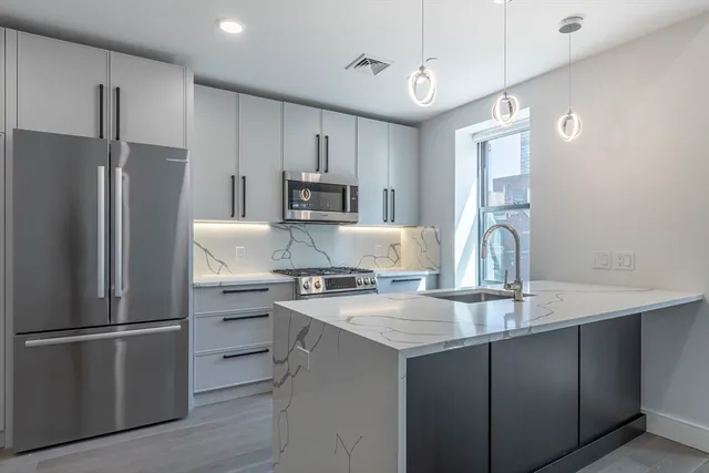 a kitchen with kitchen island granite countertop a refrigerator stove and sink