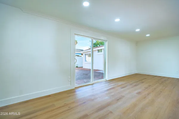 a view of an empty room with wooden floor and a window