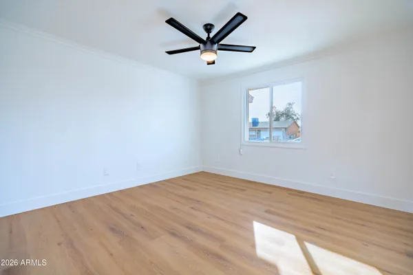 an empty room with wooden floor and ceiling fan