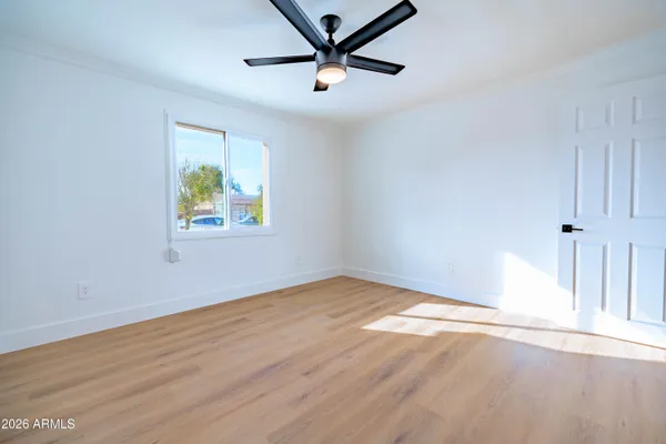 an empty room with wooden floor and ceiling fan