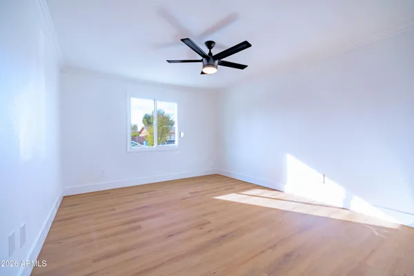 an empty room with wooden floor a ceiling fan and windows